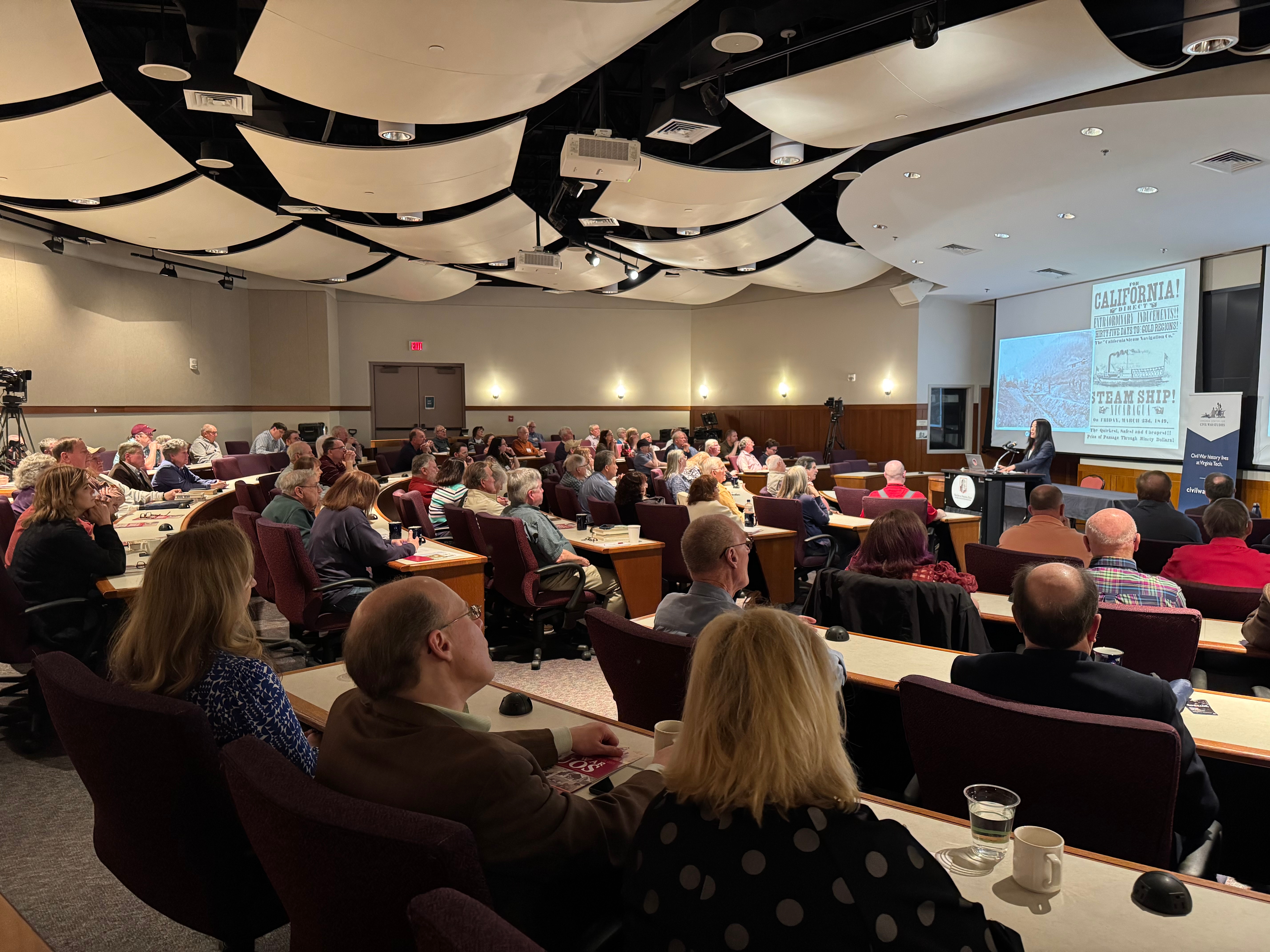 Dr. Ilyon Woo speaking to a room of more than 100 people
