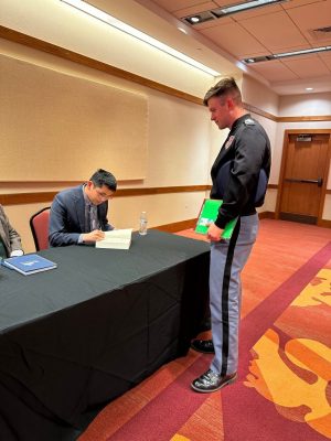 An author signing a book for a Virginia Tech cadet at the 2024 Civil War Weekend. 